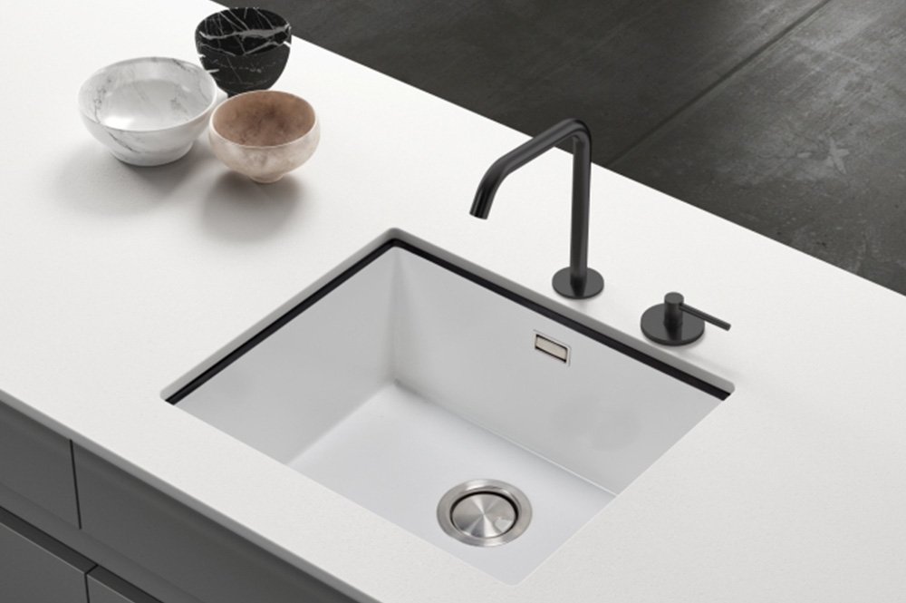 Fregadero moderno en una encimera blanca, con grifo negro