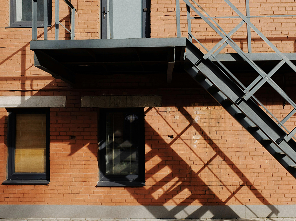 Pared exterior de un edificio con una escalera exterior metálica para acceder al primer piso