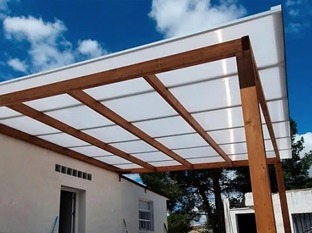 Casa de campo con una marquesina con estructura de madera y techo de placas de policarbonato