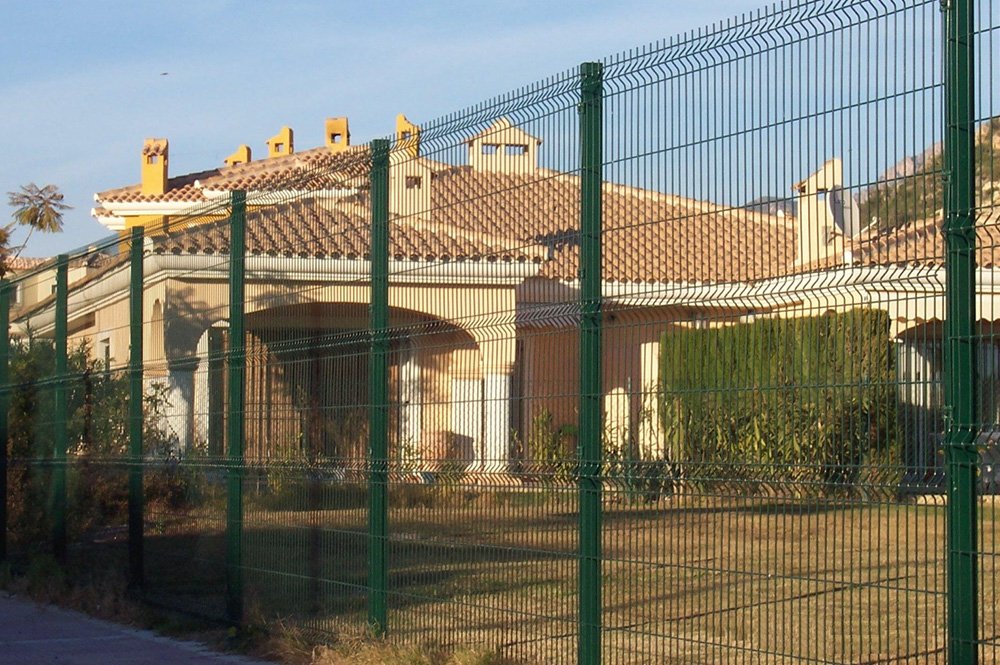 Vista de una casa de campo a través de una valla metálica