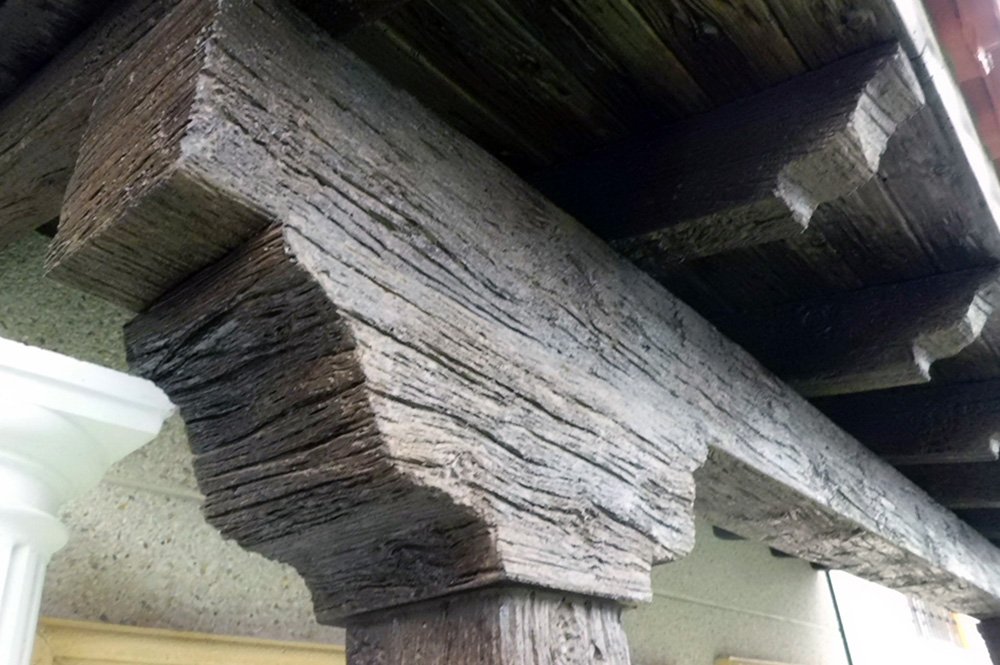 Primer plano de una viga de imitación madera sosteniendo el alero de un tejado