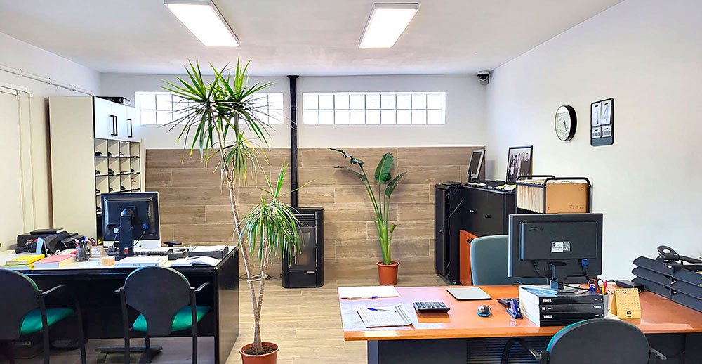 Interior de una oficina con dos puestos de trabajo con ordenadores, material de oficina y dos plantas