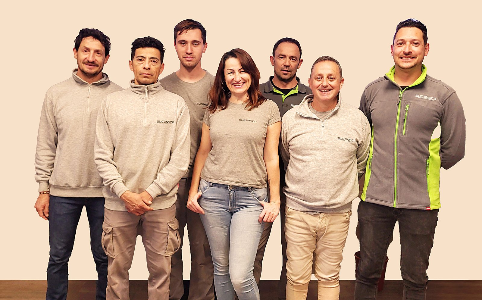 Grupo de seis hombre y una mujer con ropa de trabajo posando y sonriendo
