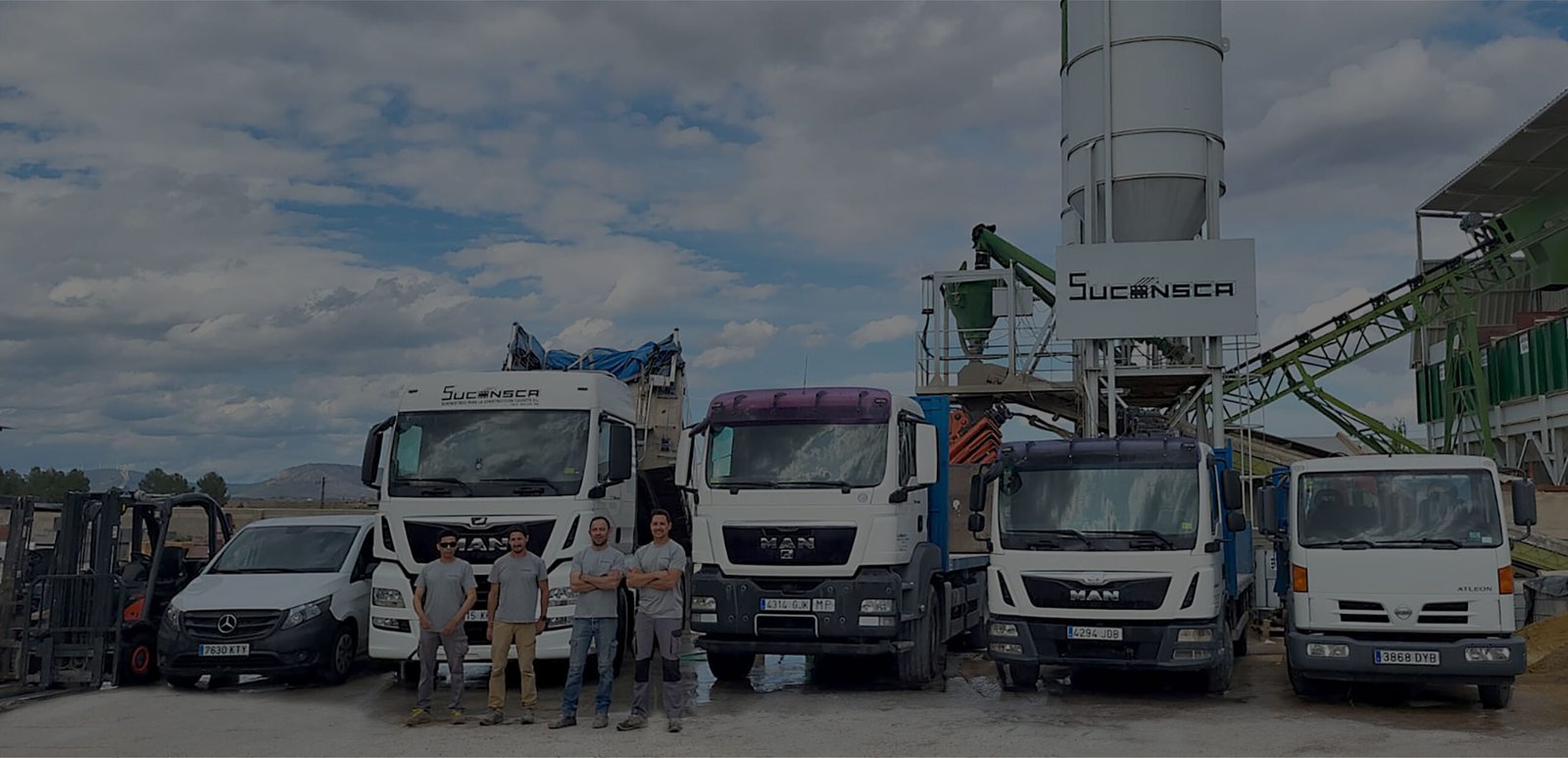 Planta de hormigón de Suconsca con varios vehículos aparcados delante y un grupo de cuatro trabajadores