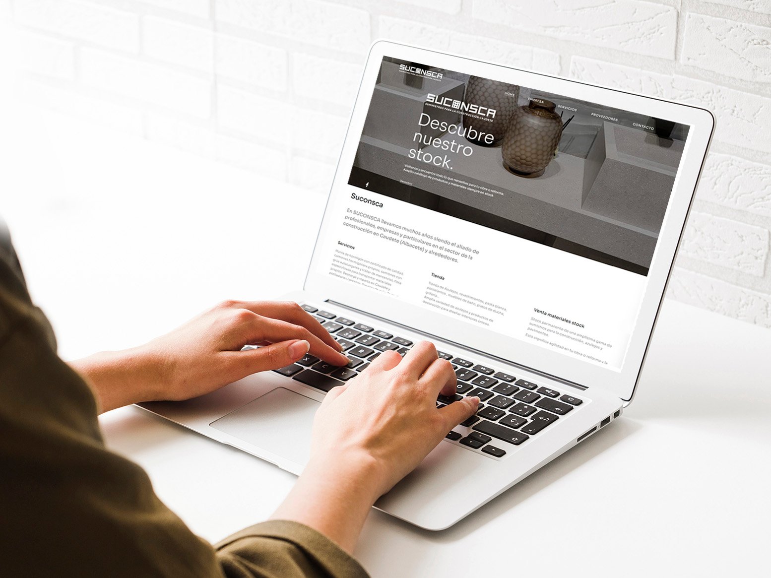 Ordenador portátil sobre una mesa con una mujer tecleando