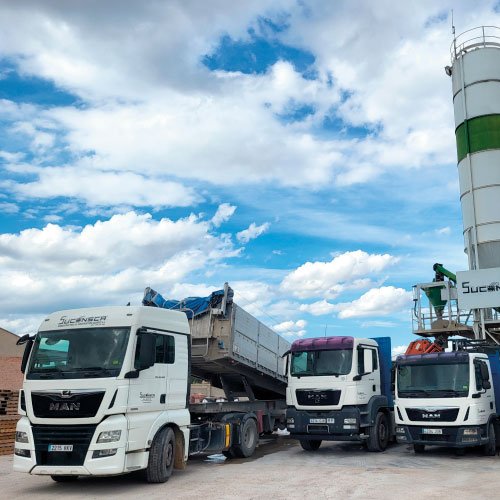 Tres camiones volquete vistos de frente, aparcados en una planta cementera.