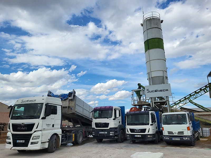 Cuatro camiones volquete aparcados en una planta cementera.