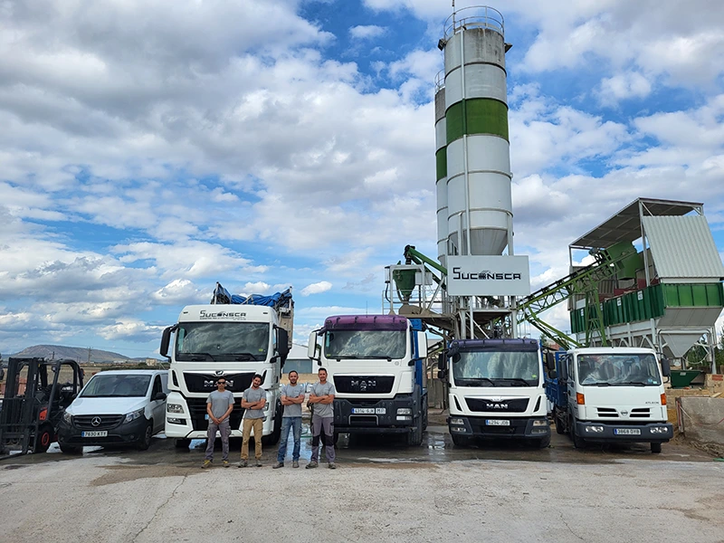 Planta de hormigón de Suconsca con varios vehículos aparcados delante y un grupo de cuatro trabajadores